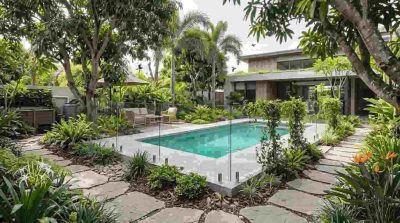 A peaceful environmentally conscious residential garden with a modern swimming pool surrounded by elegant safety fencing, native Australian plants, mature trees, natural landscaping, clean pathways in a sustainable outdoor design.